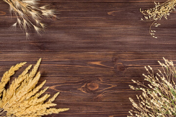 Spikelets of different plants on a wooden background. Place for an inscription. View from above.