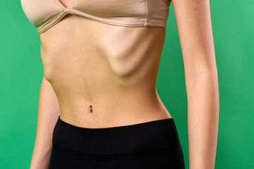 Fototapeta na wymiar Close-up slim tight woman's stomach. Skinny girl's body isolated on green background.