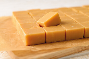 A lot of caramel vanilla fudge on a brown parchment paper. Fresh tasty candies made of milk and...
