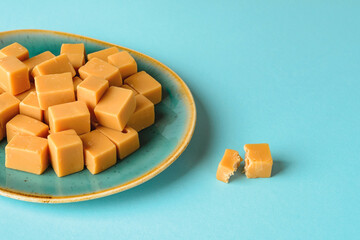 Close-up of caramel vanilla fudge on a turquoise ceramic plate over turquoise background. Fresh...