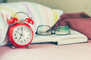 Red alarm-clock in the badroom, morning time.	
