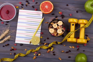 Healthy food and diet concept. Notepad and diet food with measure tape. Yellow dumbbells with...