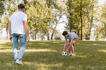 selective focus of teenager son touching football near father