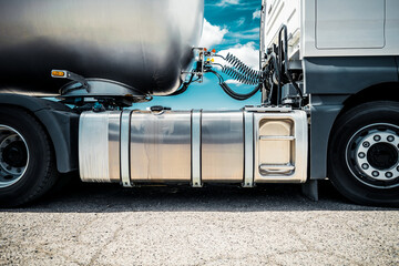 Truck with trailer, tank with flammable liquid, sunny day outside, metallic color container, blue...