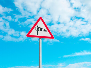 Road sign crosswind on the blue sky with clouds