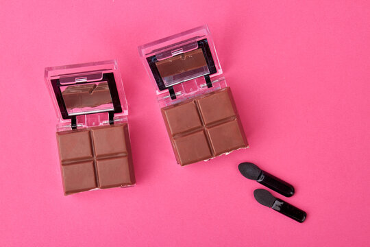 Cosmetic powder caces with chocolate. Concept of chocolate skincare mask. Isolated on pink background.