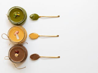 Nuts butter in jars with ingredients. Homemade raw organic peanut, hazlenut, pistachio, nuts paste butter. Top view. Copy space.