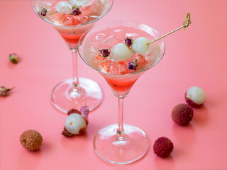 Sweet lychee liqueur on the pink background. Selective focus.
