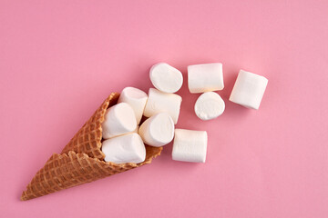 Ice-cream cone waffel with marshmallows. Isolated on pink background.