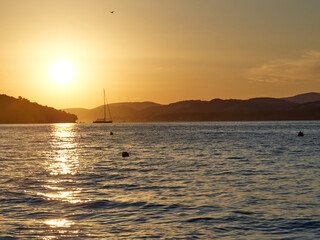 Sunset on the beach in the Croatian town of Okrug Gornji. Sailing ship on the background of mountains