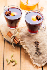 Obraz na płótnie Canvas Mulled wine on a wooden background. Autumn mulled wine and spices on burlap. Christmas hot drink in rustic style