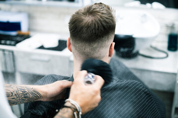Barber using brush with powder on neck of client 