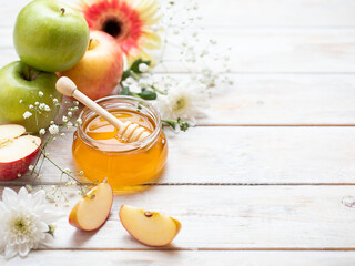 Rosh Hashanah Jewish New Year holiday concept with traditional symbols - apples, honey, pomegranate on white wooden background. Copy space.