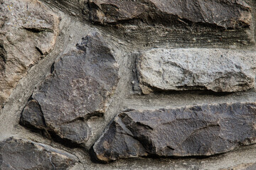 Gray wall made of stone with several shades of gray and different shapes of the stones