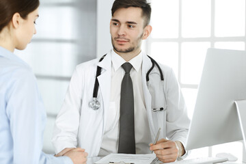 Doctor and patient. Physician man filling up medication history records form while sitting at the glass desk in medical office or clinic. Medicine and healthcare concept