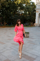 Full lenght image of pretty romantic woman in pink dress posing outdoor in old european ity.