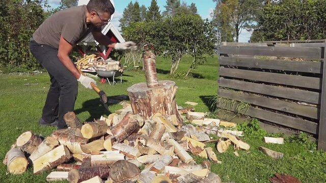 Mature Man failed when tried to chop long birch log with large metal axe with yellow wooden handle, log flew away. He does not succeed from first time. Backyard, warm sunny day, slow motion video