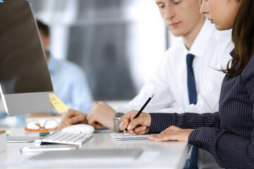 Obraz premium Business woman and man are discussing questions while using computer and blocknote in modern office, close-up. Teamwork in business