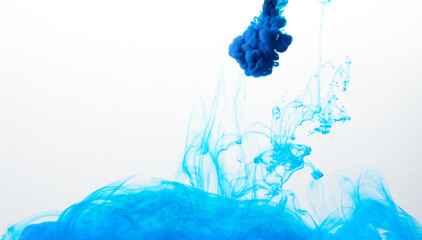 Closeup of a blue ink in water in motion isolated on white. Ink swirling underwater. Colored...