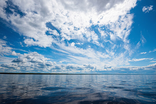 Panorama of calm lake, Kama river blue sky with clouds reflected in the water.