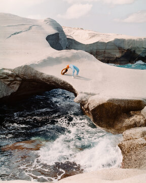 Woman doing yoga on cliff in sea