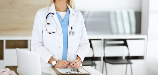 Unknown woman-doctor at work in clinic. Female physician controls medication history record and medical exam results, close-up. Medicine concept