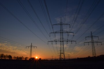 Fototapeta na wymiar Sonnenaufgang an einem Feld mit Strommasten