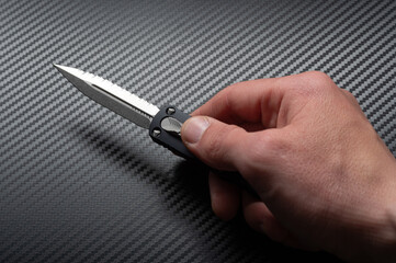 A knife with a double-sided sharpened blade. Automatic folding knife. Knife in hand.