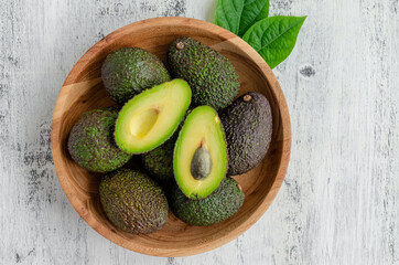 Fresh ripe avocado with leaves in a wooden plate on a wooden background. Healthy food concept. Top...