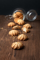 Cookies fall out of the glass jar on a wooden table