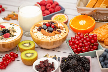 Breakfast Served in the morning with Butter bread and corn flakes Whole grains and raisins with milk in cups and Strawberry, Blueberry, Raspberry, Kiwi, Fresh Orange  on the breakfast table.