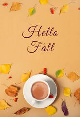 A cup of coffee and yellow autumn leaves on a beige background. Autumn time and home comfort, fall season.
