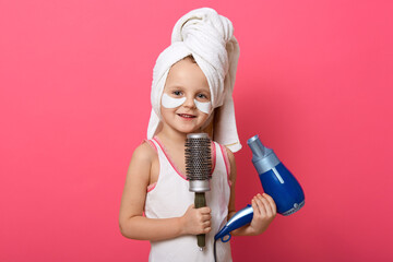 Beautiful cute girl with blue hair dryer and comb in hands, has white towel on head and patches...