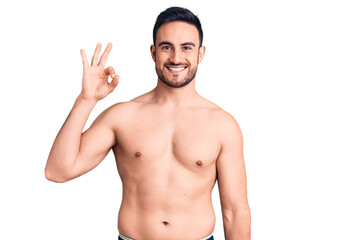 Fototapeta premium Young handsome man wearing swimwear smiling positive doing ok sign with hand and fingers. successful expression.