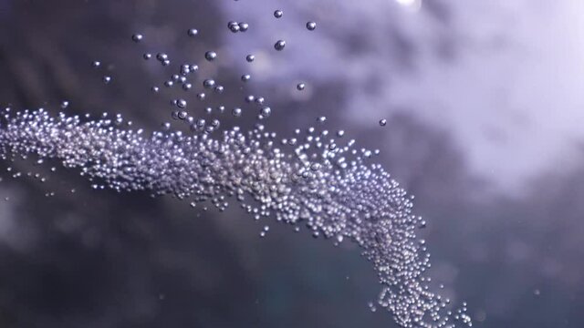 air bubbles underwater in blue water moving strange some in focus some out of focus making nive background shapes with sun rays and sun shine