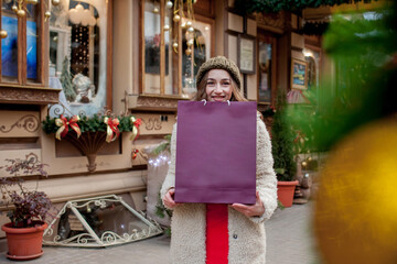 Happy girl holds paperbags with symbol of sale in the stores with sales at Christmas, around the city. Concept of shopping, holidays, happiness, Christmas Sales.