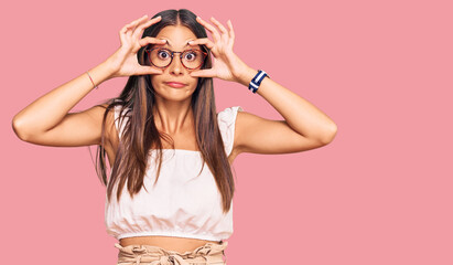 Young hispanic woman wearing casual clothes and glasses trying to open eyes with fingers, sleepy...