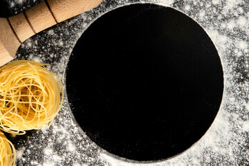 Freshly cooked pasta is lying on a dark surface dusted with flour. Italian pasta. Tagliatelle. Raw pasta. Italian pasta recipe. Top view, copy space