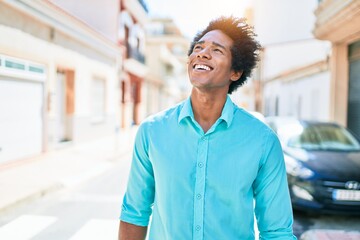 Young handsome african american man wearing casual clothes smiling happy. Standing with smile on face looking to the side walking at town street.