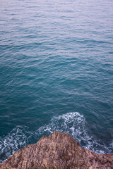 Top view of waves breaking slightly on cliff rocks