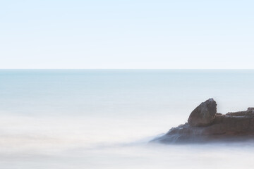 Silk effect long exposure wave softly breaking on coastal rock