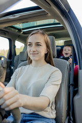Mother gives the phone little boy sitting in a car seat. Safety of transportation of children.