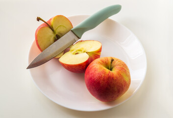 Ripe red apples in a plate with knife. Cut an Apple before eating to follow diet