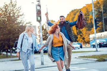 Obraz premium Group of tourists enjoying on vacation, young friends having fun walking on city.