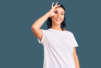 Fototapeta premium Young woman wearing casual clothes doing ok gesture with hand smiling, eye looking through fingers with happy face.