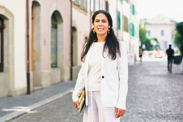 Beautiful middle age woman posing outside, wearing white jacket