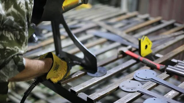 Close-up blacksmith welder in protective mask works with metal using a welding machine, bright sparks.