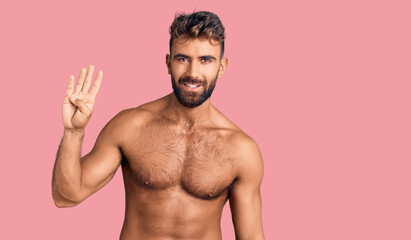 Fototapeta premium Young hispanic man wearing swimwear shirtless showing and pointing up with fingers number four while smiling confident and happy.
