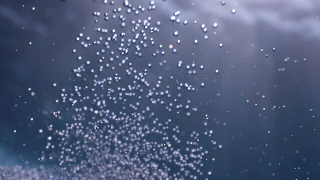 air bubbles underwater in blue water moving strange some in focus some out of focus making nive background shapes with sun rays and sun shine
