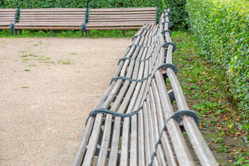 A recreation bench made of boards and wrought iron in a city park in summer